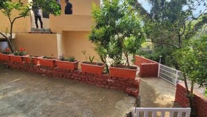 A residential area with a paved driveway, a brick wall, and a white gate. - Villa Kartina 3 BHK near Sattal Lake (Bhowāli)