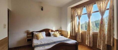 Un dormitorio con cama de madera, ventilador de techo y ventana con cortinas.