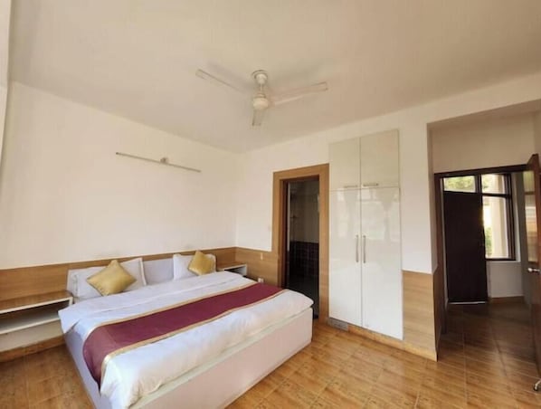 Un dormitorio con cama, armario, ventilador de techo y puerta que da a otra habitación.