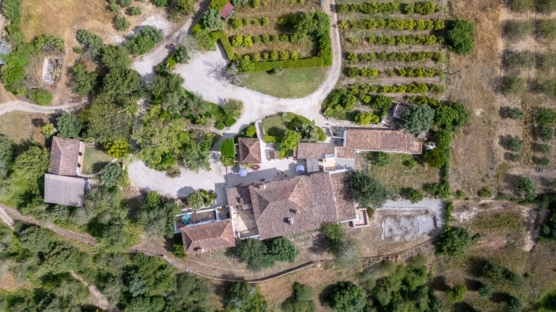 Vista aérea de una propiedad con varias construcciones, un patio central y jardines circundantes.