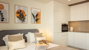 Un apartamento moderno con cama, mesita de noche y una pequeña kitchenette.