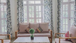 Una habitación con un conjunto de sofá, una mesa de centro y cortinas.