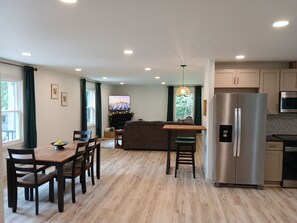 A modern kitchen with a built-in refrigerator, a microwave, and a dining area with wooden chairs and a table. - Serene 4-bedroom house with hot tub and a game room in charming Conestoga (Conestoga)
