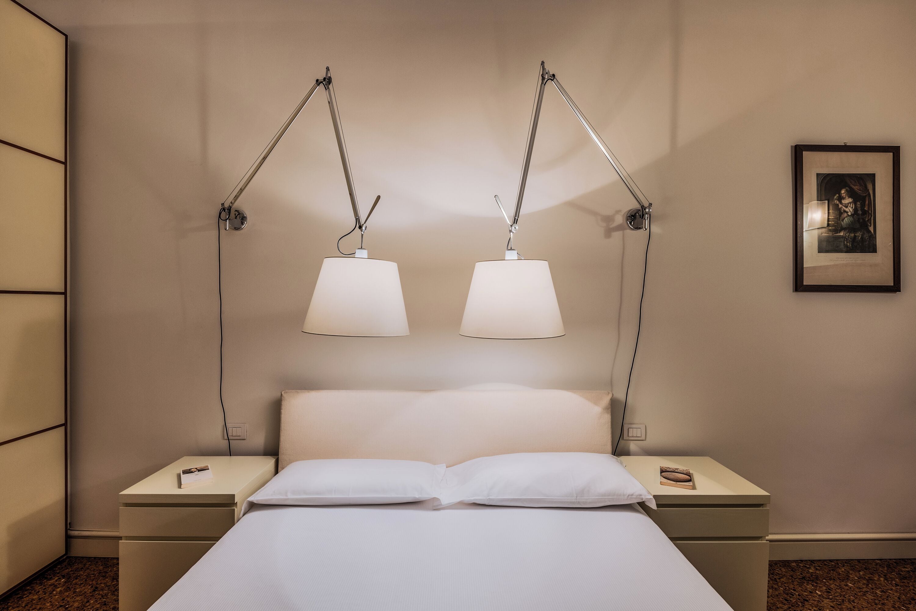 Ein ordentlich eingerichtetes Hotelzimmer mit einem Bett, zwei Nachttischen und zwei Wandleuchten.