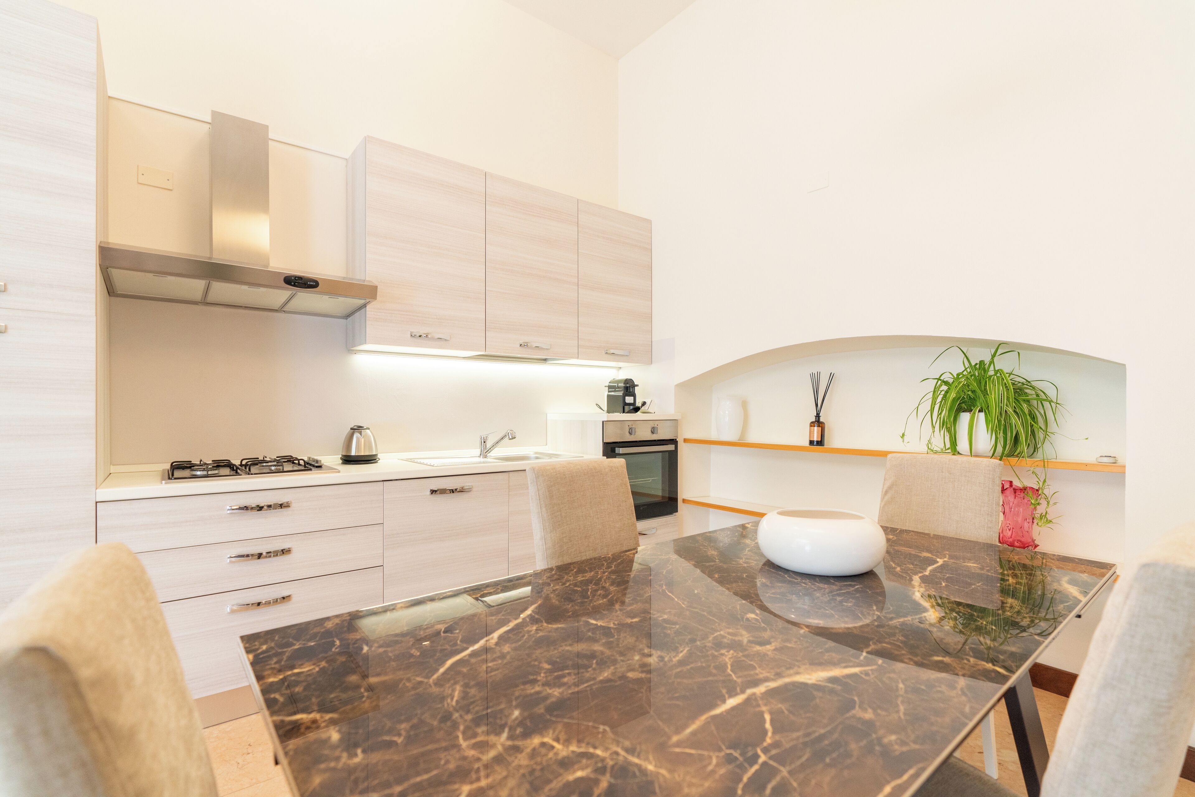 A modern kitchen with a marble countertop, white cabinets, and a built-in oven.