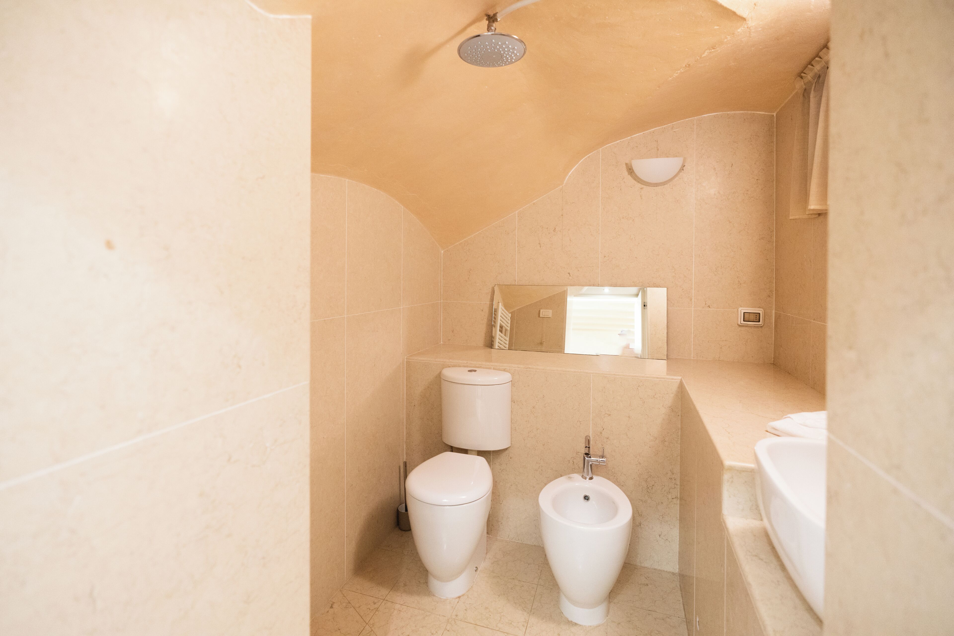 A bathroom with a toilet, bidet, and shower.
