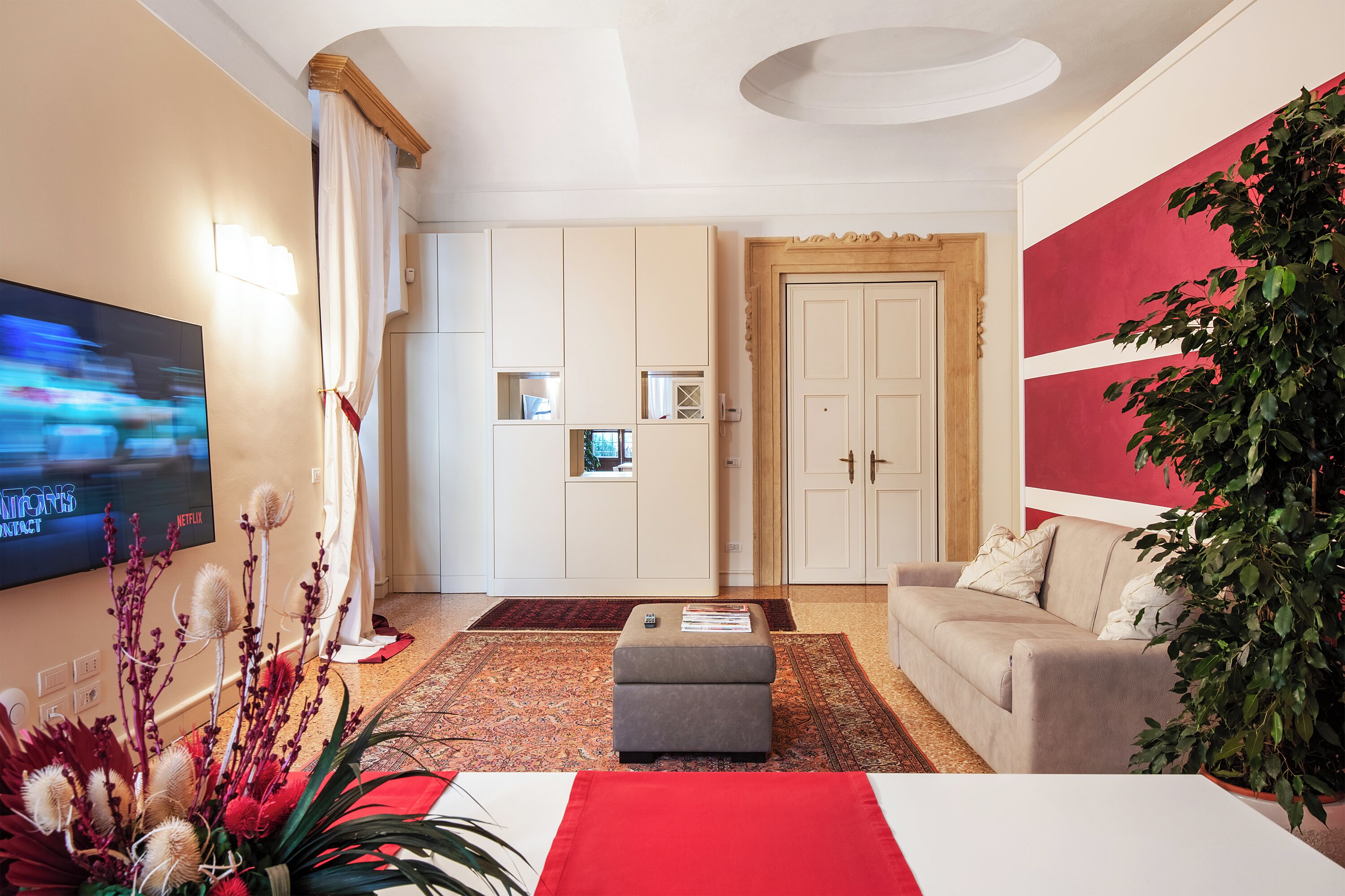 Un salon moderne avec un téléviseur à écran plat, un canapé, une table basse et une grande plante.
