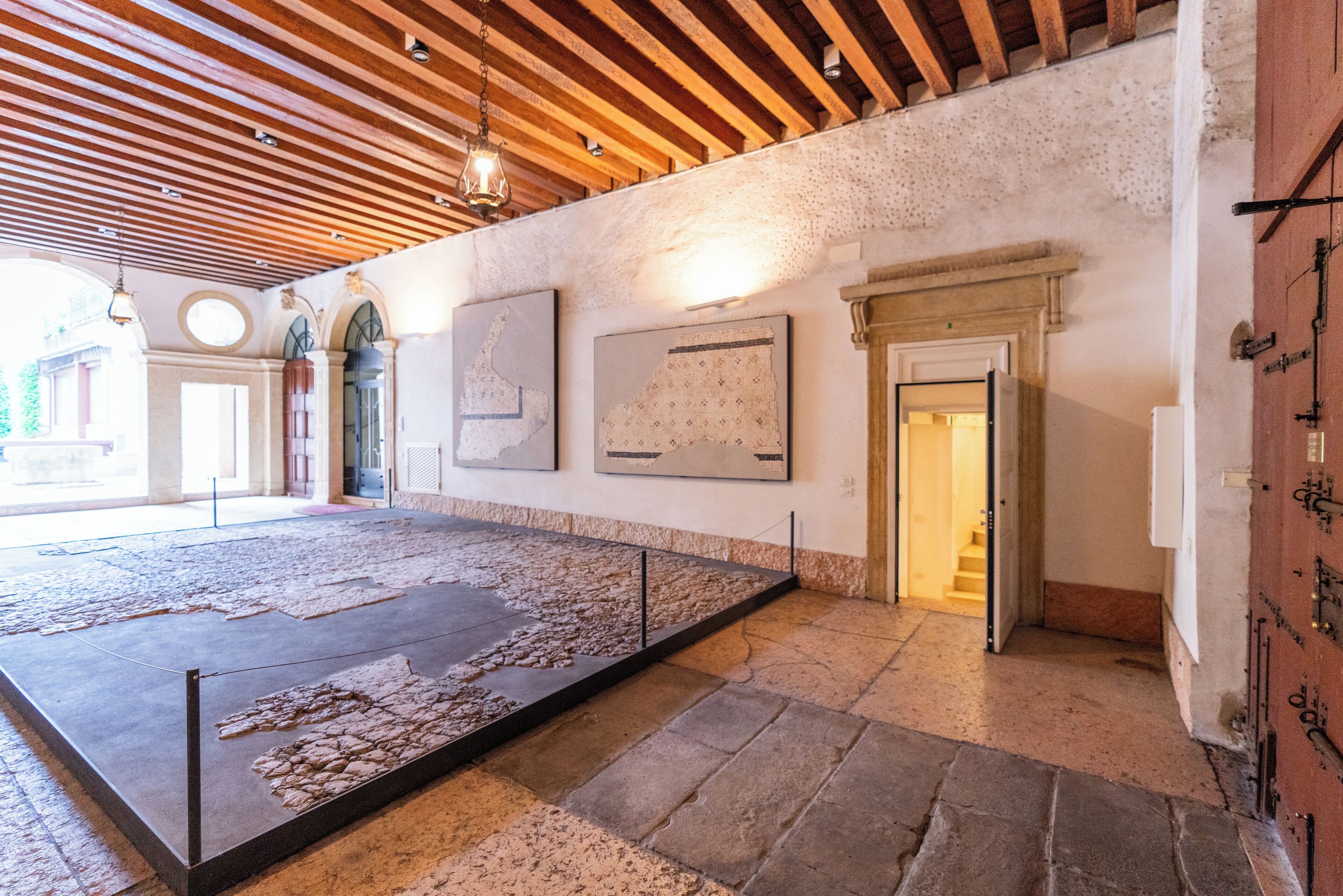 Een ruime kamer met een hoog houten plafond, stenen vloer en een groot presentatiegedeelte met artefacten.