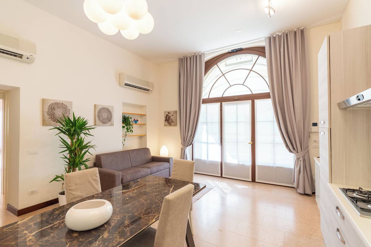 Una sala de estar moderna con una mesa de comedor, un sofá y un ventanal con cortinas.