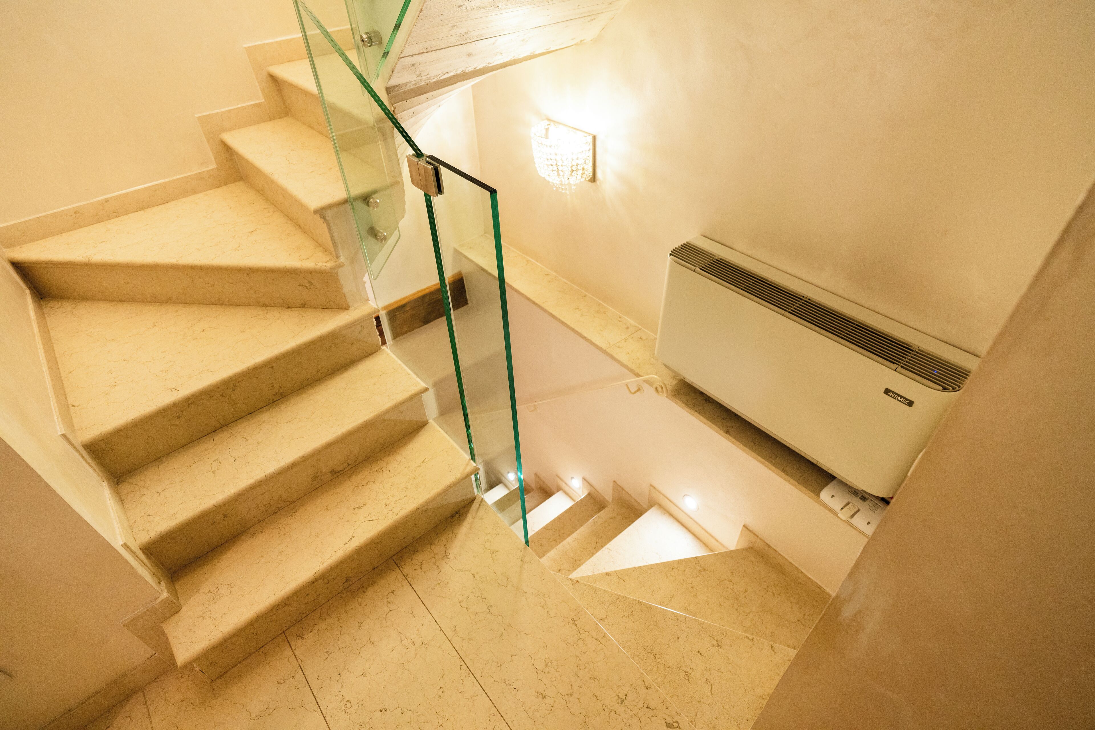 Un escalier avec des rampes en verre et un climatiseur fixé au mur.