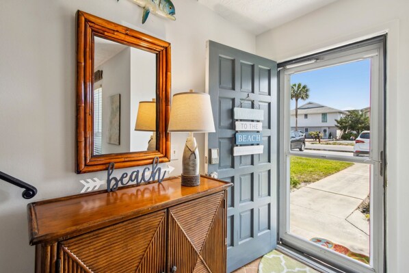 A wooden console table with a mirror above it, a lamp, and a 'beach' sign.