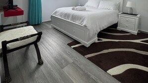 Een slaapkamer met een bed, nachtkastjes, een stoel, een raam met gordijnen en een airconditioning.