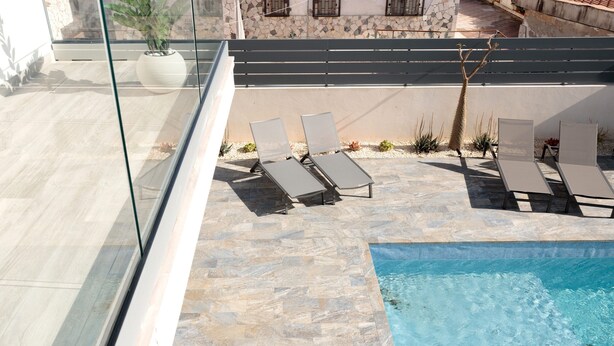 A rooftop pool area with lounge chairs and a potted plant.