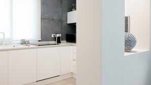 A modern kitchen with white cabinets, a grey backsplash, and a black microwave.