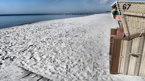 A beach with a wooden walkway leading to a beach chair area. - HUUS BADSTAVEN – Holiday Apartment Leuchtturm in Burg's Most Beautiful Alley (Fehmarn)