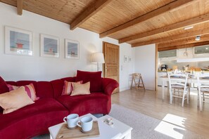 Una sala de estar con un sofá rojo, una mesa de centro blanca y un techo de madera.