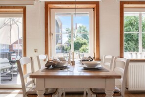 Un comedor con una mesa de madera, sillas blancas y vistas al exterior.