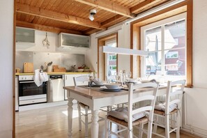 Una cocina moderna con vigas de madera, una mesa de comedor para cuatro personas y vistas al exterior.