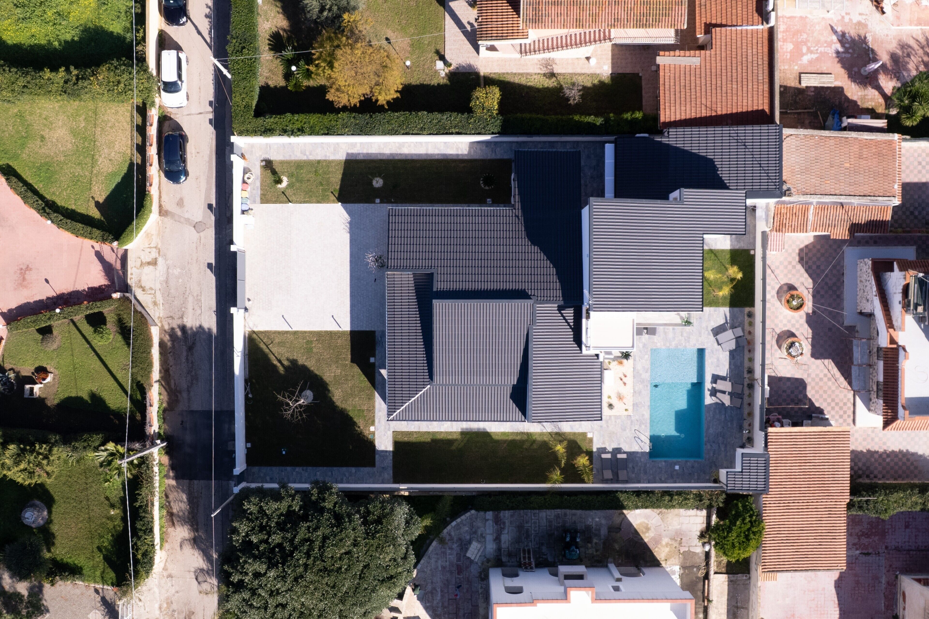 Vue aérienne d’un quartier résidentiel avec une piscine, des toits recouverts de tuiles et des espaces verts.