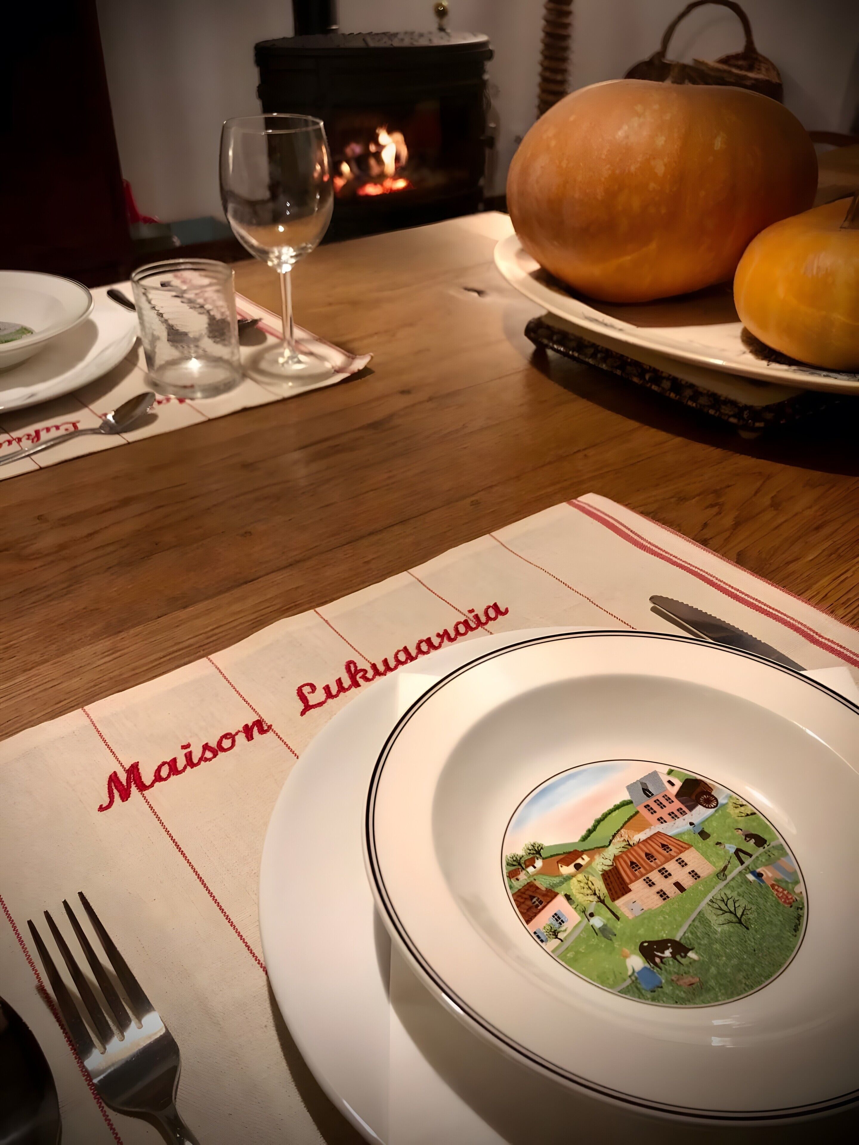 Une table dressée pour le repas, avec des assiettes, un verre, une fourchette, un couteau et une citrouille.
