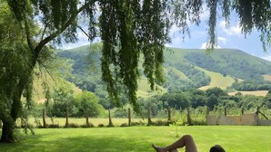 A person relaxing on a lawn chair with a dog, surrounded by greenery and hills. - Guest Room 'Olceiry' with Mountain View, Private Garden and Wi-Fi (Iholdy)