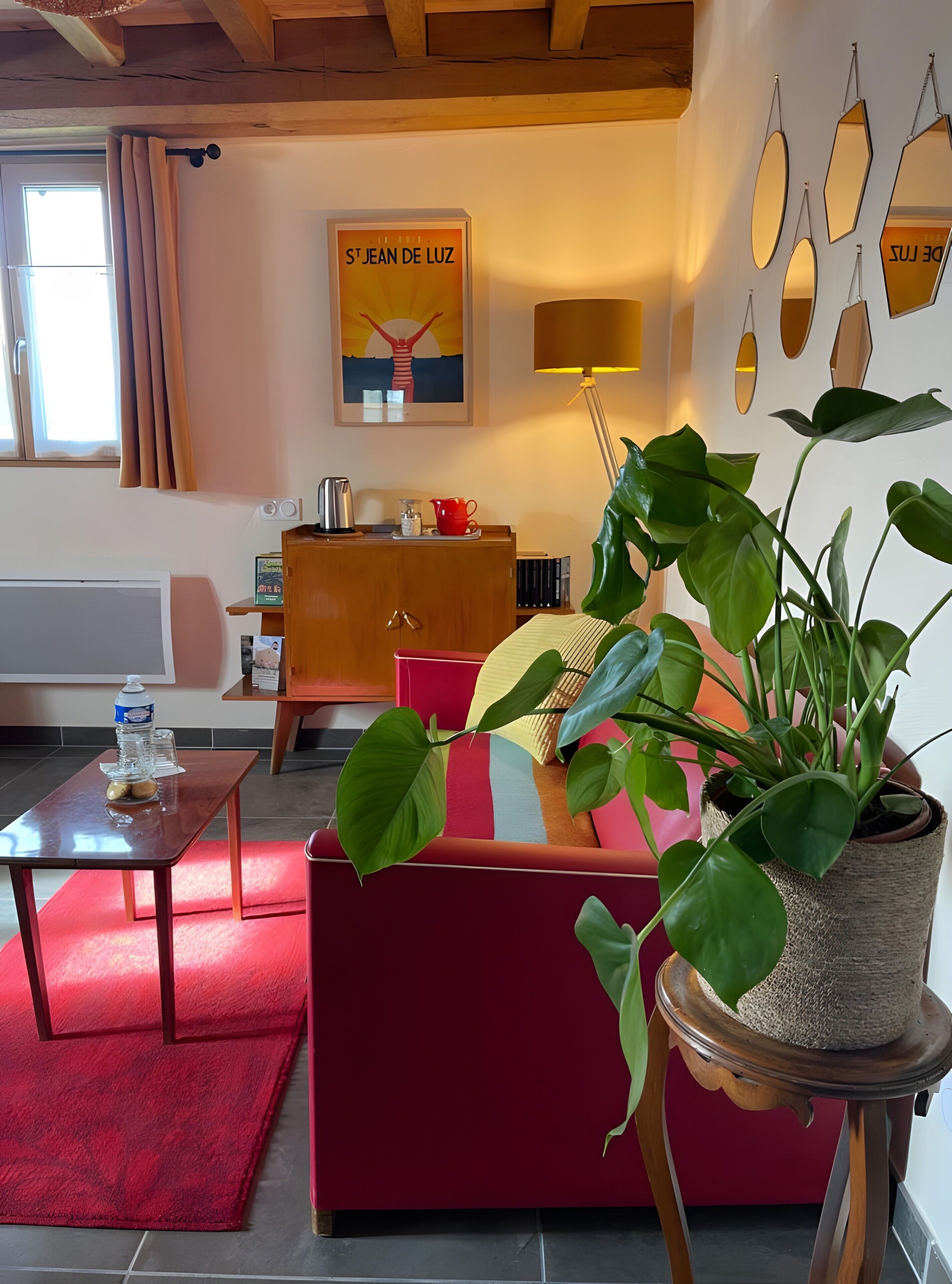 Un salon chaleureux avec un canapé, une table basse, une plante en pot, un meuble en bois et une affiche accrochée au mur.