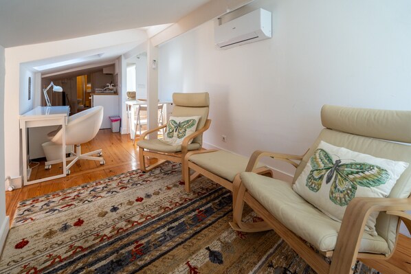 A modern living room with a sofa, two armchairs, a desk, and a patterned rug. - Bairro Alto Tiny Studio by Homing (Lisbon)