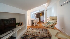 Una sala de estar moderna con televisor de pantalla plana, un sofá, un escritorio y una silla.