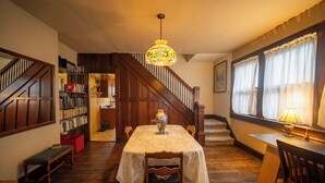 Un comedor con una mesa de madera, sillas, un jarrón y una escalera que lleva a otra habitación.