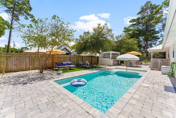 Un jardin avec une piscine, des meubles de jardin et une clôture en bois.