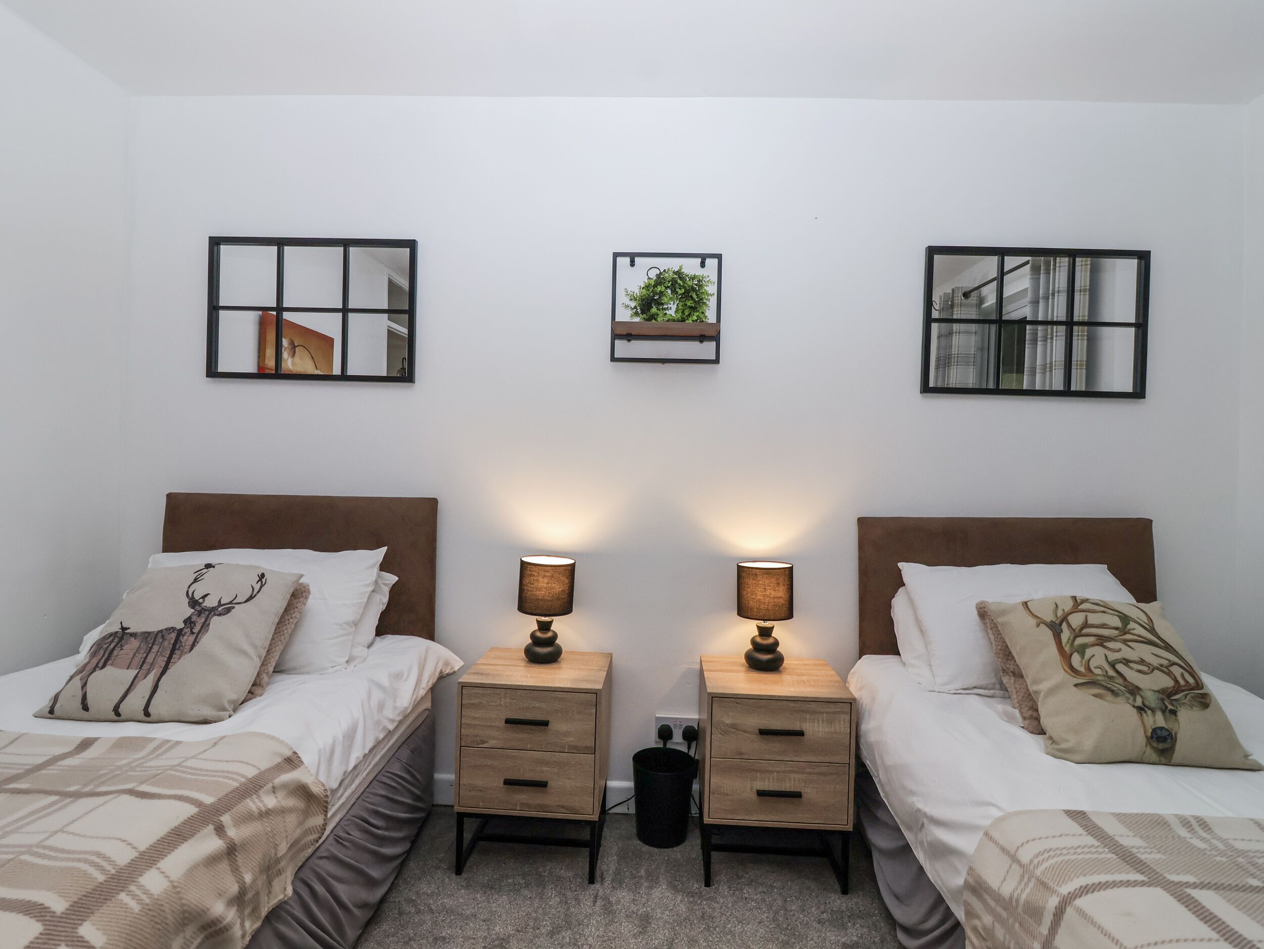 Habitación doble con dos camas, cada una con cabecera, mesitas de noche con lámparas y una obra de arte colgada en la pared.