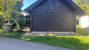 A small, dark wooden cabin with a sloped roof and a small window.