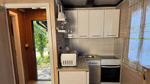 A compact kitchen with white cabinets, a built-in microwave, a sink, and a dishwasher.