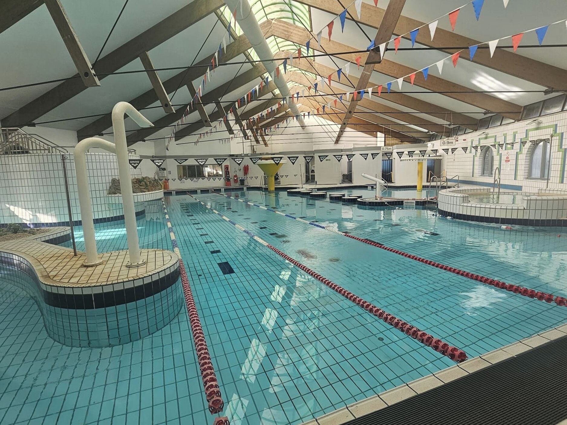 En inomhuspool med banor, en hoppställning och ett kaklat golv.