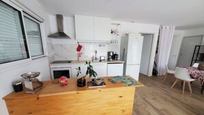 Una cocina compacta con armarios blancos, encimera de madera y un comedor con mesa y sillas.