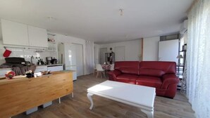Una sala de estar moderna con una mesa de comedor de madera, un sofá rojo y una mesa de centro blanca.