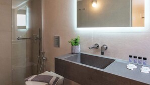 A modern bathroom with a glass shower enclosure, a large mirror, and a dark countertop with toiletries. - Casa Lakka 2 - Trendy Studio in Mykonos Town (Lakka Mikonos)