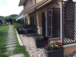 Et hus med en terrasse, udendørs møbler og plantekasser.