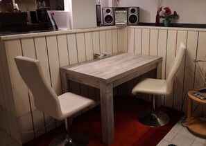 A small kitchen with a wooden table and two white chairs, a red carpet, and a potted plant on the counter. - Studio 'Jülich' with Private Terrace, Shared Garden and Wi-Fi (Weil am Rhein)