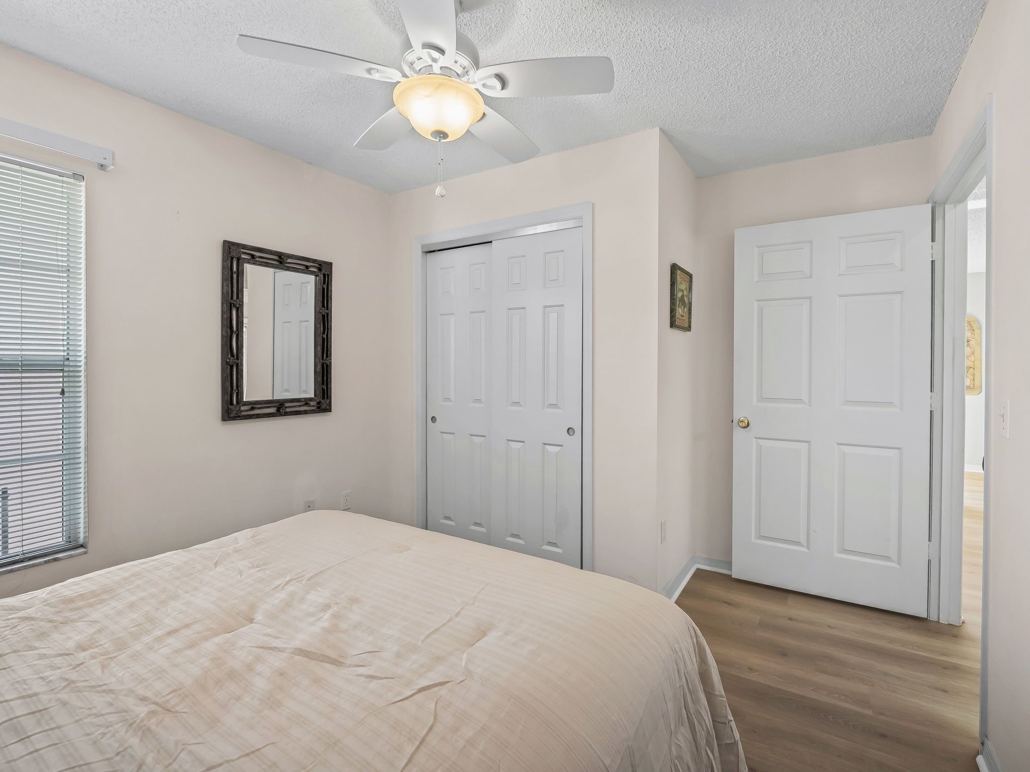 Une chambre à coucher avec un lit, un ventilateur de plafond, une porte et une fenêtre.