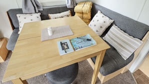 Habitació acollidora amb una taula de fusta, un sofà gris i una finestra amb cortines.