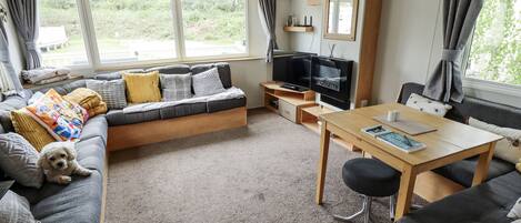 A cozy living room with a sofa, a small table, a TV, and a window with curtains.