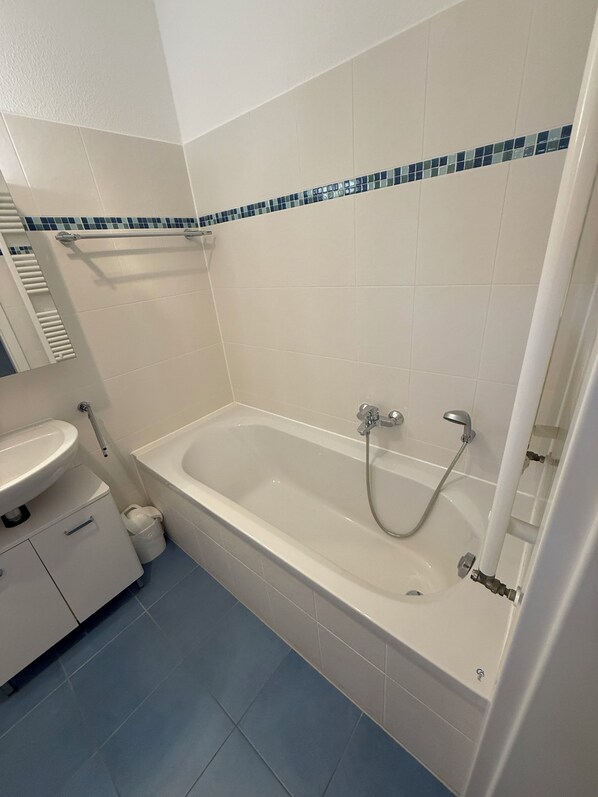 A bathroom with a bathtub, a sink, and a mirror.