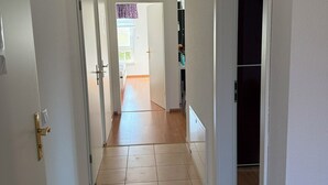 A hallway with a tiled floor leading to a room with a window and a door. - MLK-Lodge: Your vacation apartment on the Mittelland Canal (Sehnde)