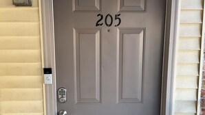 Eine graue Tür mit der Nummer 205, einem Zahlenschloss und einem kleinen Fenster darüber.