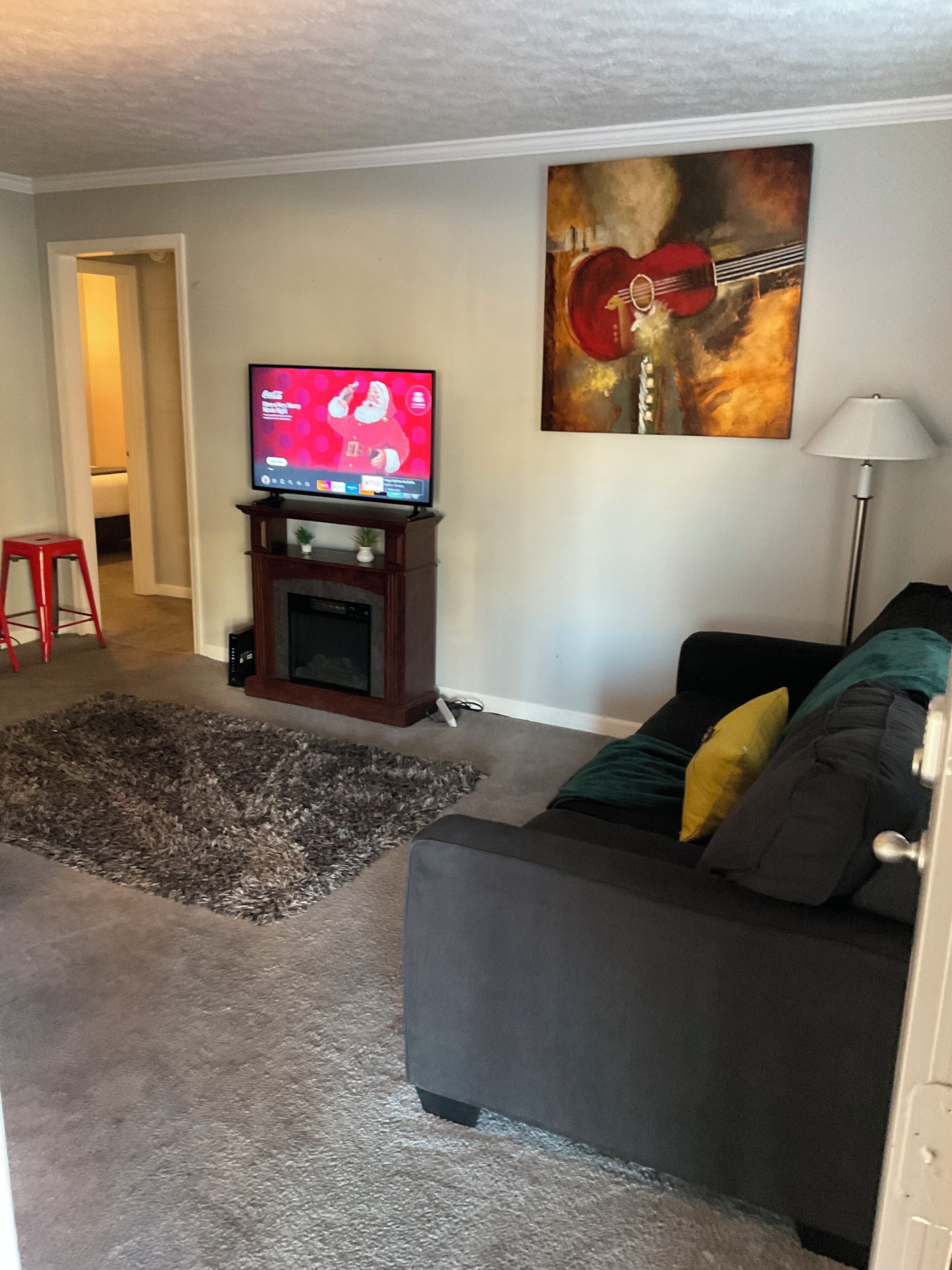 Ein Wohnzimmer mit Fernseher, Kamin, Sofa und einem Bild an der Wand.