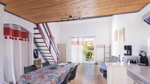A dining area with a table, chairs, and a kitchen area with appliances.