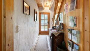 A hallway with wooden walls, a door at the end, and a bulletin board with various items. - Apartment 1 with Shared Garden, Balcony and Wi-Fi (Todtmoos)