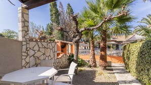 An outdoor patio with a table and chairs, surrounded by stone walls and palm trees.