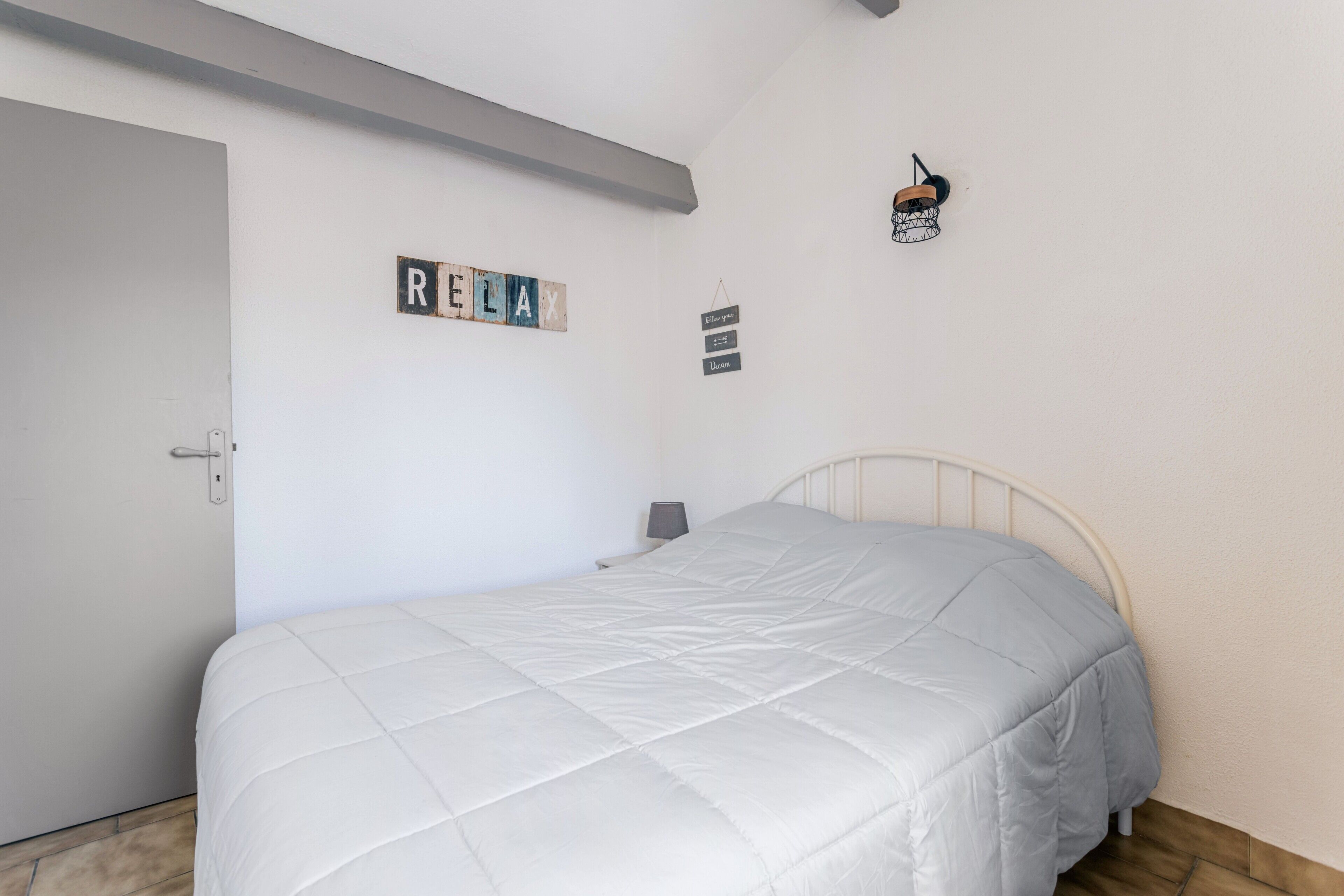 Une chambre à coucher avec un lit, une porte et un mur sur lequel est affiché un panneau indiquant « RELAX ».